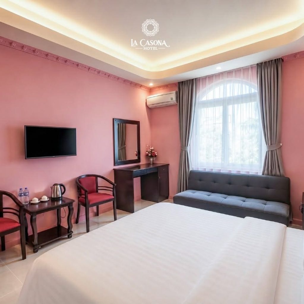 Bright executive room with pink walls, sofa, and natural light at La Casona Hotel Phu My Hung