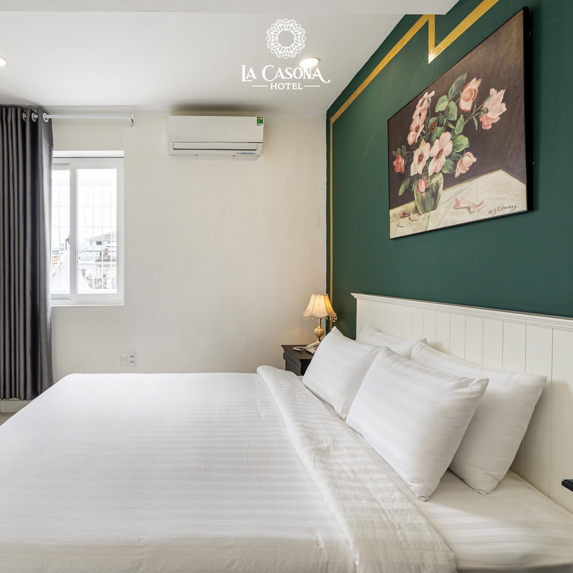 Phòng nghỉ thanh lịch với mảng tường xanh lục bảo và tranh hoa tại La Casona Hotel Hưng Gia 3